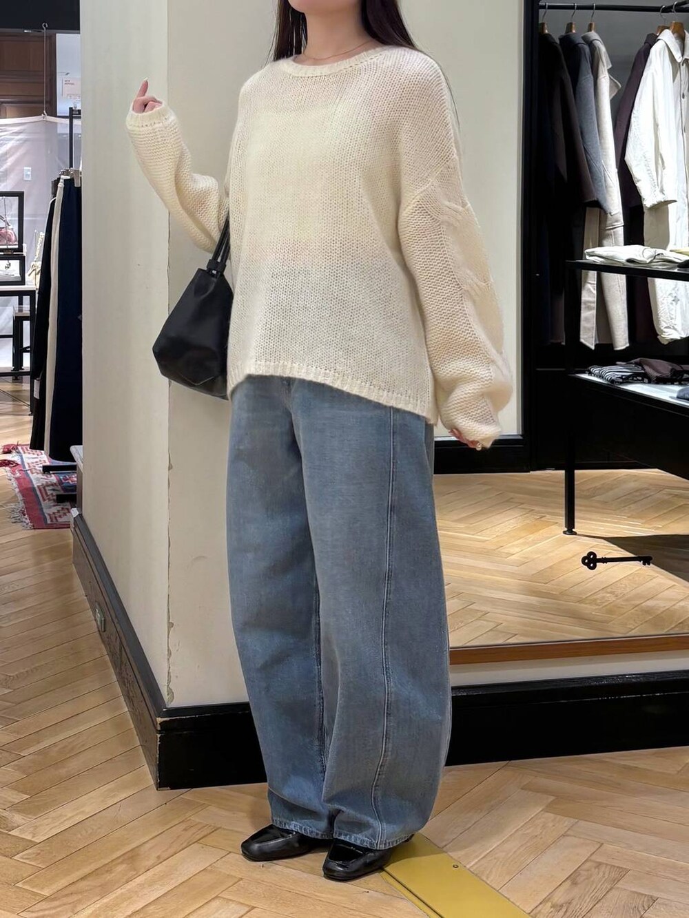 ブルー系のデニムパンツ、ブラック系のローファー、ホワイト系のニット/セーターを着用したレディースの秋コーディネートの3枚目の写真