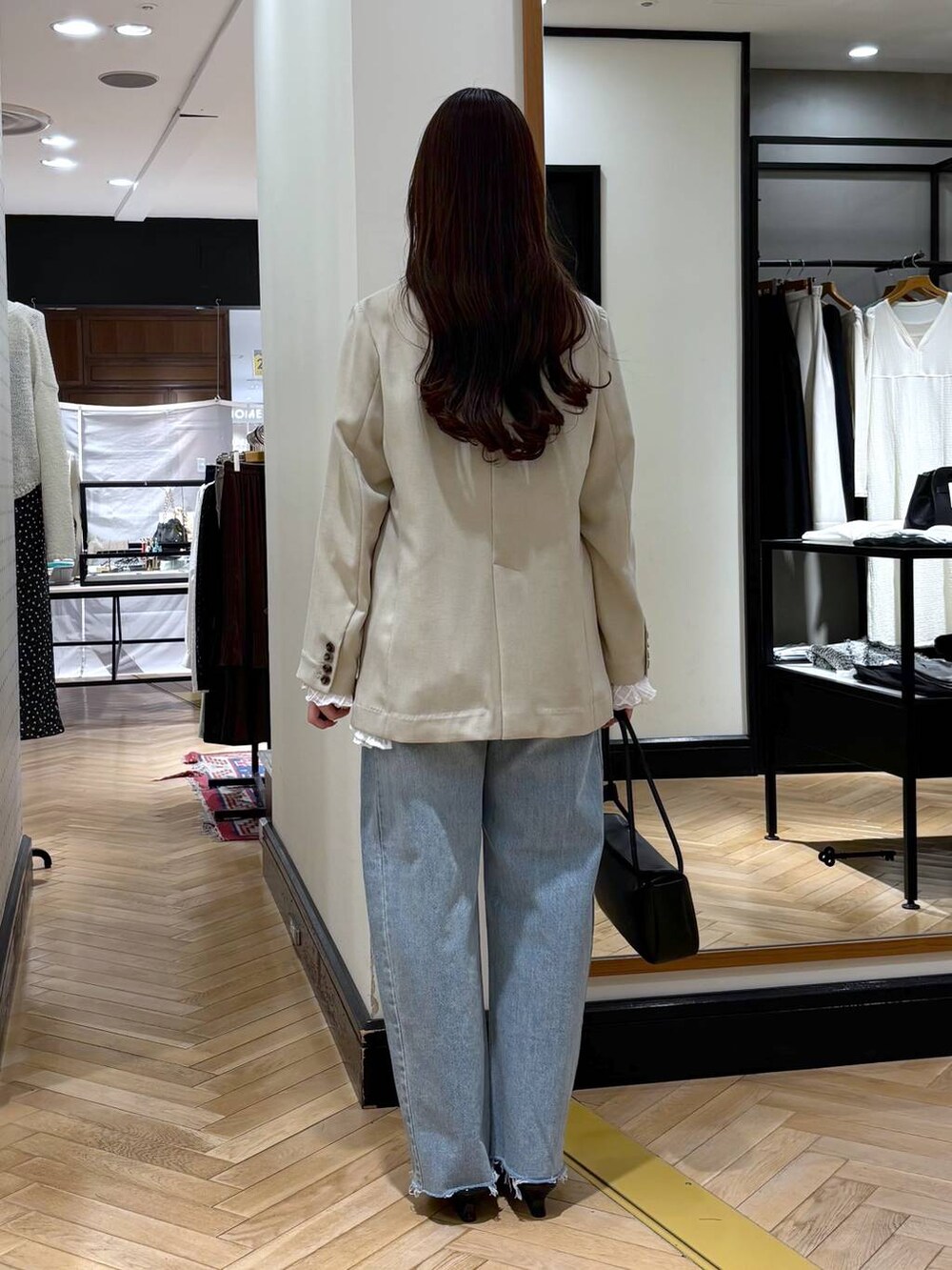 ブルー系のデニムパンツ、ベージュ系のノーカラージャケット、ブラック系のショルダーバッグを着用したレディースの春コーディネートの4枚目の写真