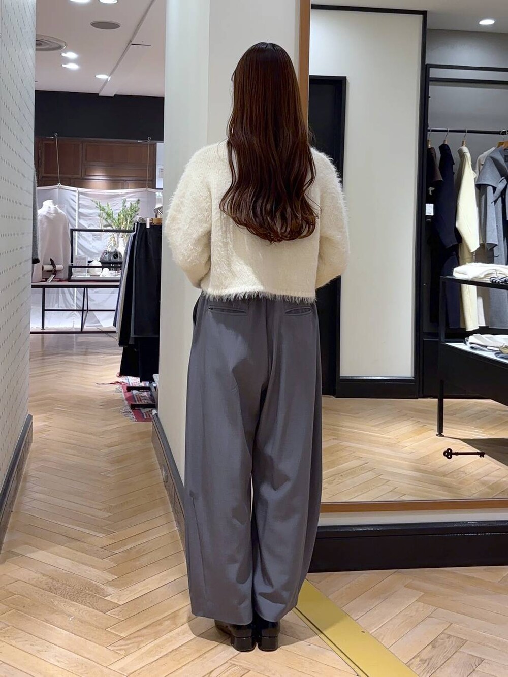 グレー系のスラックス、ブラック系のローファー、ブラック系のショルダーバッグを着用したレディースの冬コーディネートの3枚目の写真