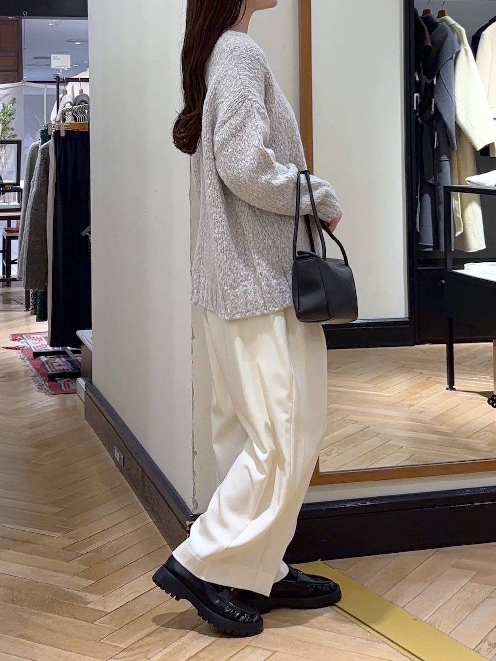 ホワイト系のスラックス、ブラック系のローファー、グレー系のニット/セーターを着用したレディースの冬コーディネートの2枚目の写真