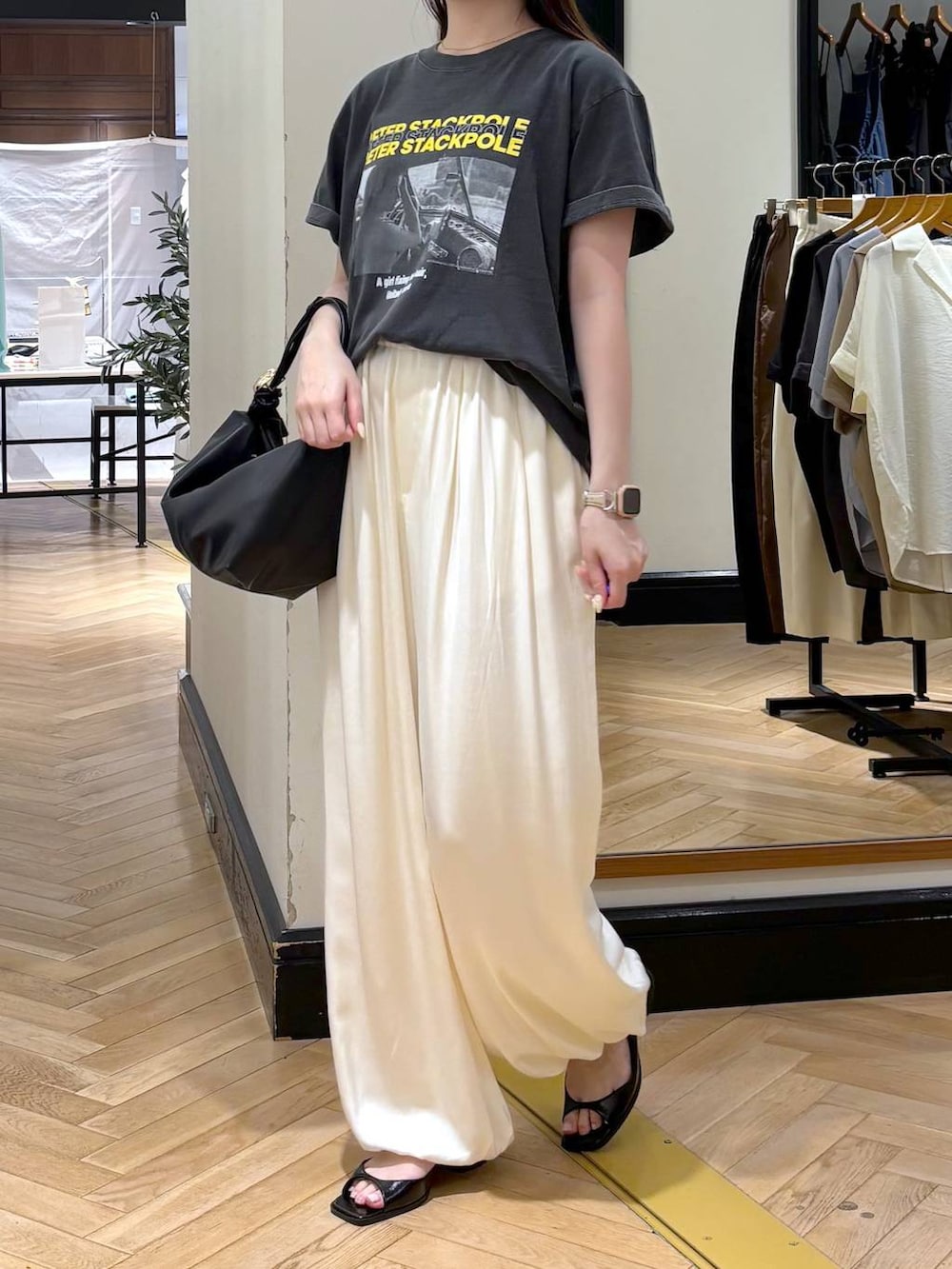 ブラック系のショルダーバッグ、グレー系のTシャツ/カットソー、ブラック系のパンプスを着用したレディースの夏コーディネートの3枚目の写真