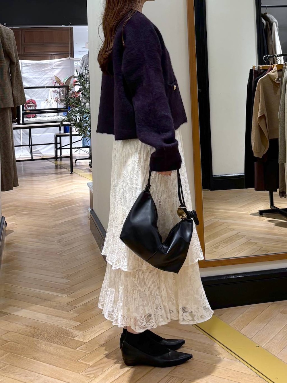 ブラック系のパンプス、ホワイト系のスカート、ブラック系のショルダーバッグを着用したレディースの秋コーディネートの3枚目の写真