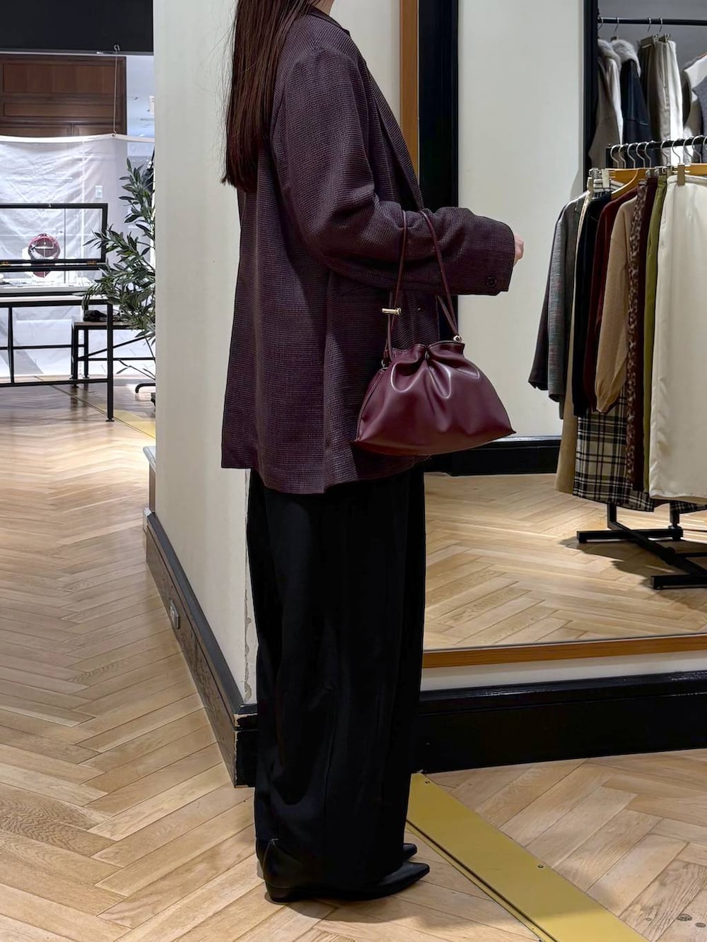 レッド系のショルダーバッグ、ブラック系のパンプス、ブラック系のスラックスを着用したレディースの秋コーディネートの4枚目の写真