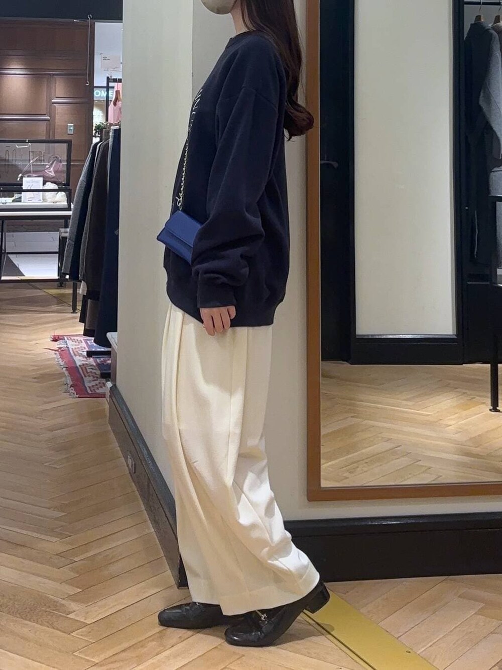 ホワイト系のスラックス、ブラック系のローファー、ブルー系のスウェットを着用したレディースの秋コーディネートの4枚目の写真