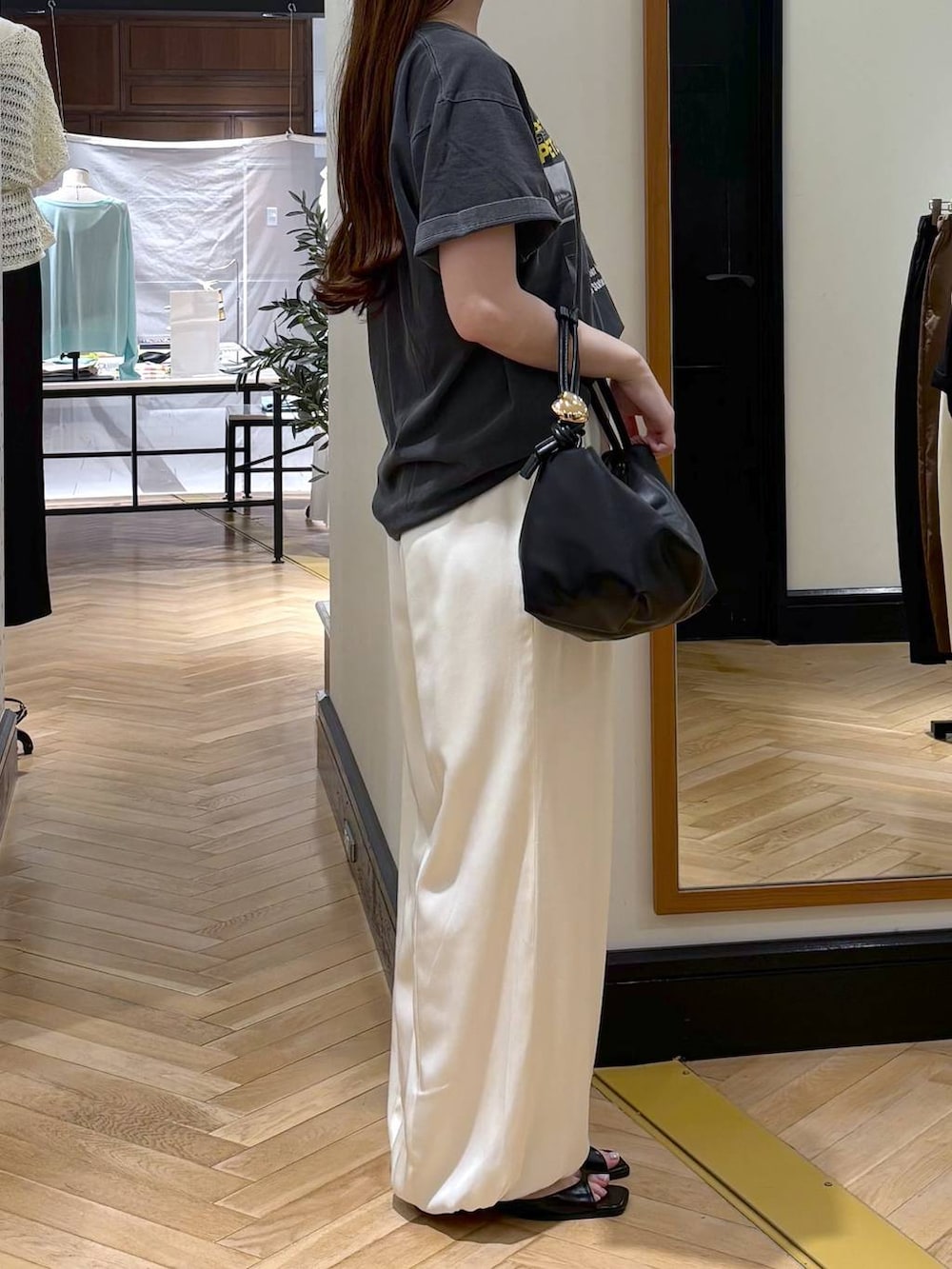 ブラック系のショルダーバッグ、グレー系のTシャツ/カットソー、ブラック系のパンプスを着用したレディースの夏コーディネートの2枚目の写真