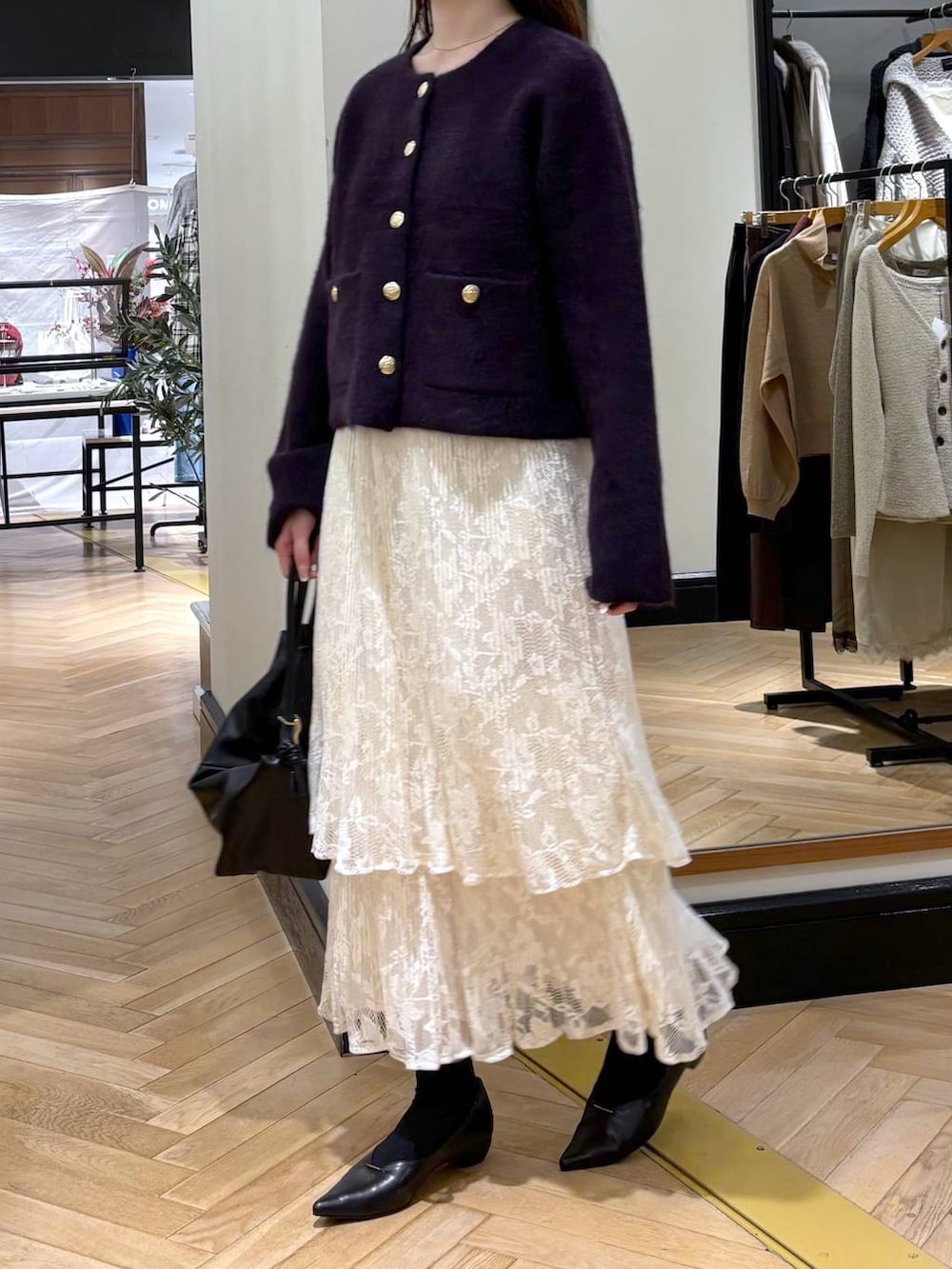 ブラック系のパンプス、ホワイト系のスカート、ブラック系のショルダーバッグを着用したレディースの秋コーディネートの2枚目の写真