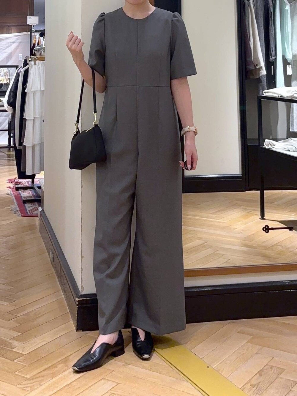 ブラック系のパンプス、ブラック系のショルダーバッグ、グレー系のつなぎ/オールインワンを着用したレディースの秋コーディネートの2枚目の写真