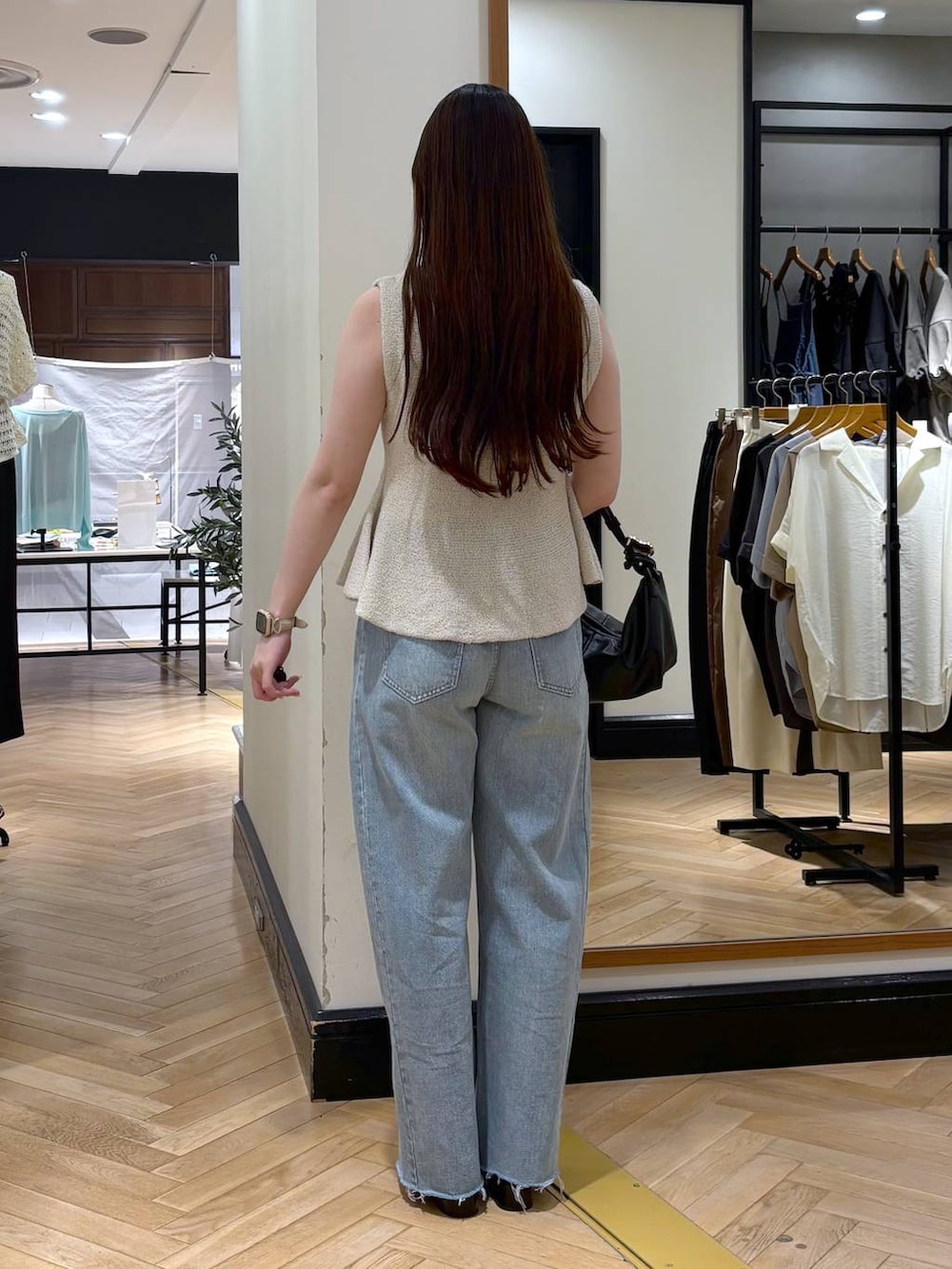 ホワイト系のベスト、ブラック系のショルダーバッグ、ブルー系のデニムパンツを着用したレディースの夏コーディネートの4枚目の写真