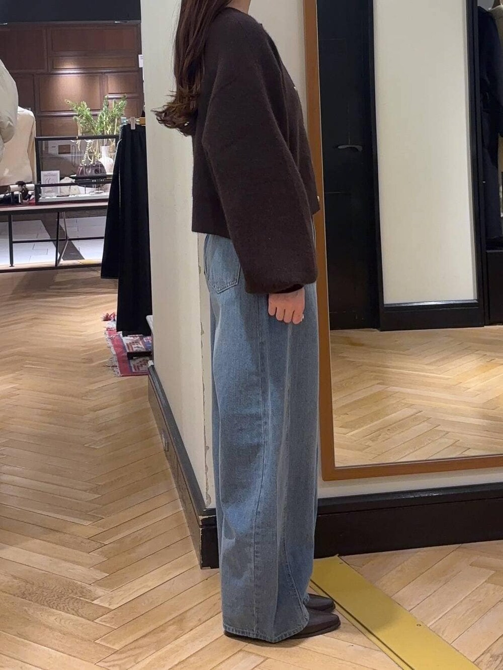 ブルー系のデニムパンツ、ブラウン系のブーツ、ベージュ系のハンドバッグを着用したレディースの冬コーディネートの2枚目の写真