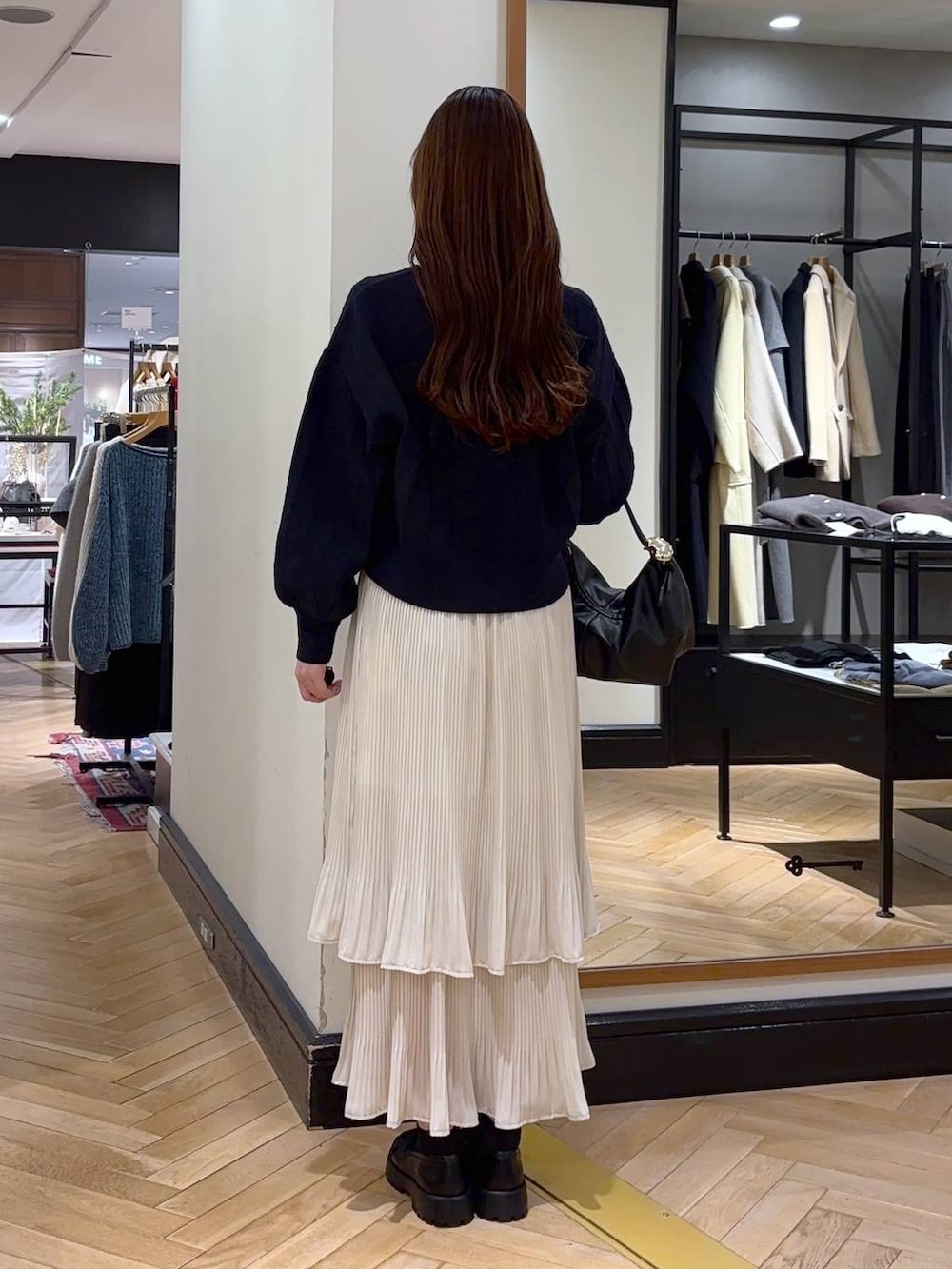 ホワイト系のスカート、ブラック系のショルダーバッグ、ブルー系のカーディガン/ボレロを着用したレディースの冬コーディネートの4枚目の写真