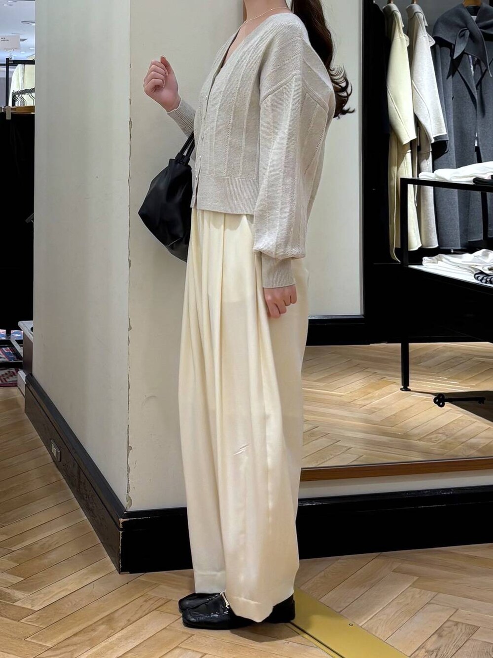 ホワイト系のスラックス、ブラック系のローファー、ブラック系のショルダーバッグを着用したレディースの冬コーディネートの3枚目の写真