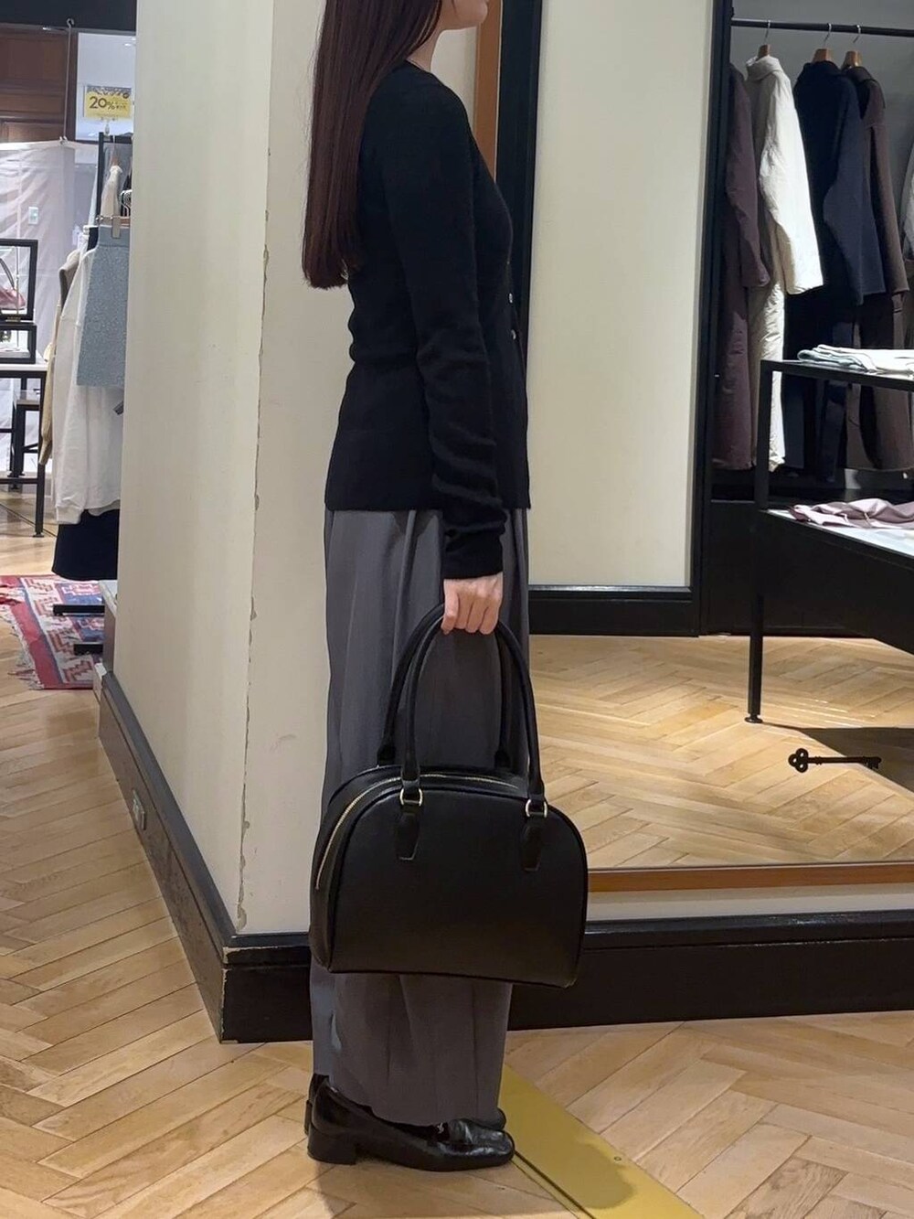 グレー系のスラックス、ブラック系のローファー、ブラック系のボストンバッグを着用したレディースの秋コーディネートの3枚目の写真