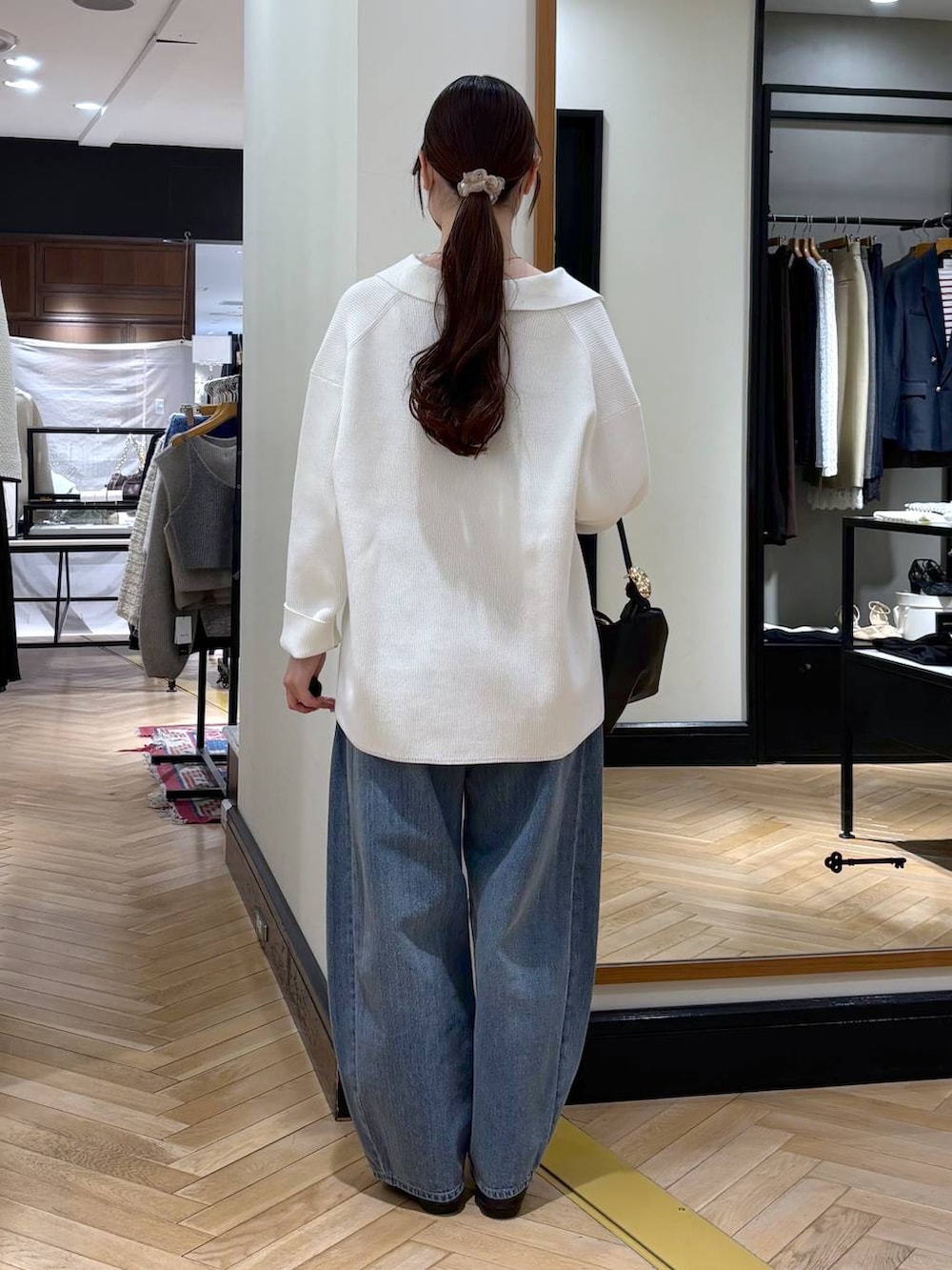 ブルー系のデニムパンツ、ブラック系のショルダーバッグ、ホワイト系のニット/セーターを着用したレディースの冬コーディネートの5枚目の写真