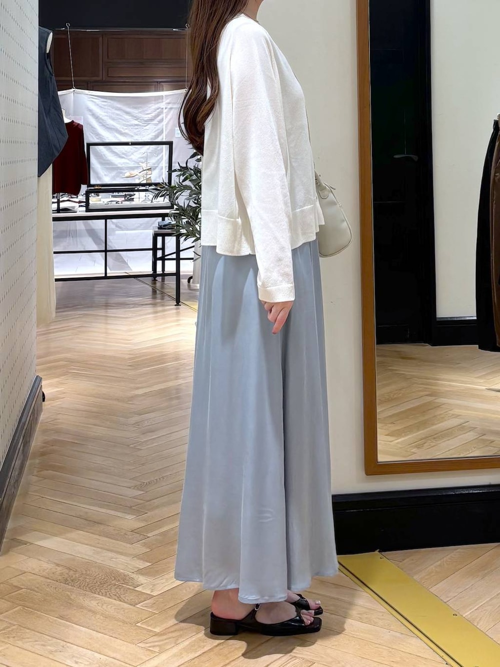ブルー系のスカート、グレー系のニット/セーター、ブラック系のパンプスを着用したレディースの夏コーディネートの2枚目の写真