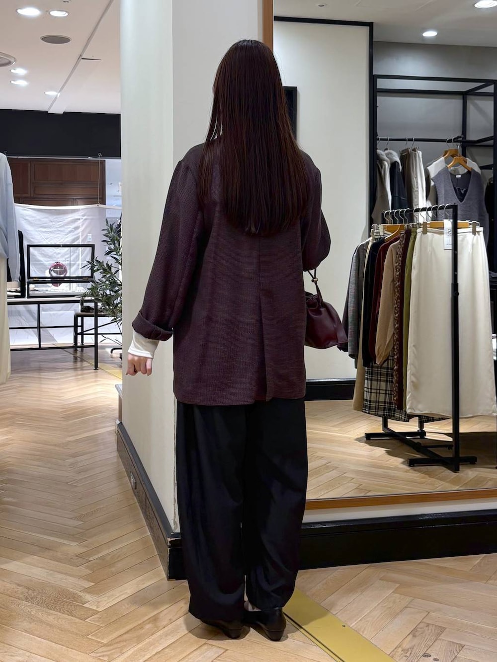レッド系のショルダーバッグ、ブラック系のパンプス、ブラック系のスラックスを着用したレディースの秋コーディネートの5枚目の写真