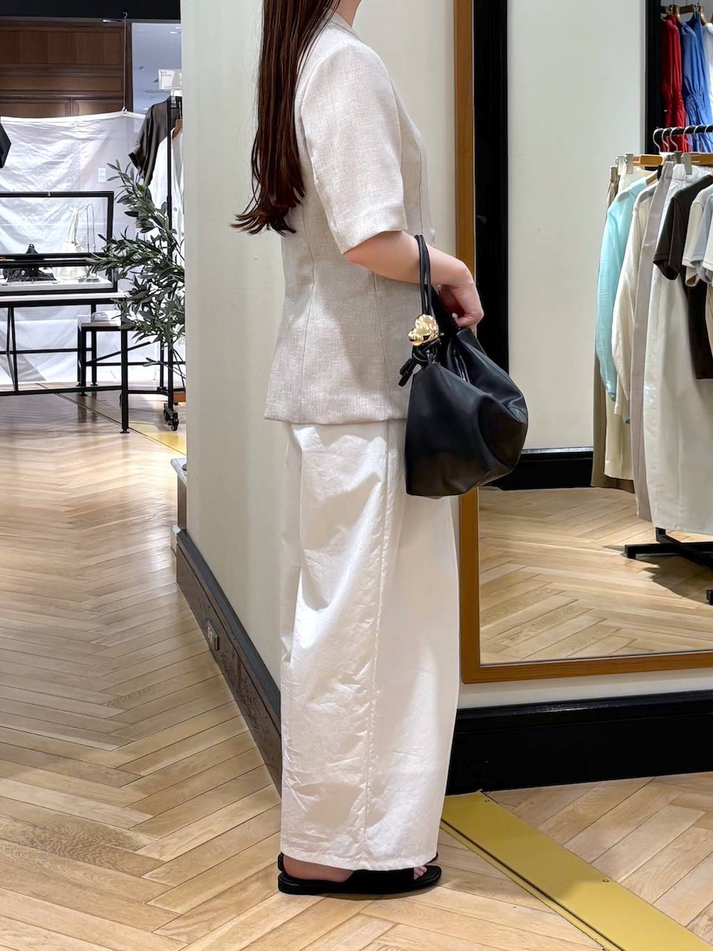 ブラック系のショルダーバッグ、ホワイト系のその他パンツ、ベージュ系のノーカラージャケットを着用したレディースの春コーディネートの2枚目の写真