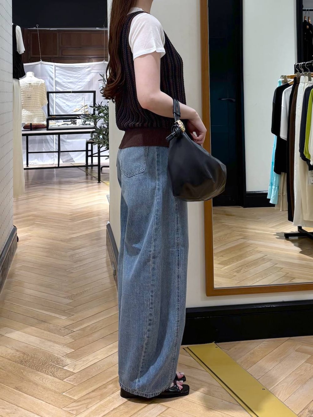 ブラック系のショルダーバッグ、ブルー系のデニムパンツ、ブラック系のパンプスを着用したレディースの夏コーディネートの3枚目の写真