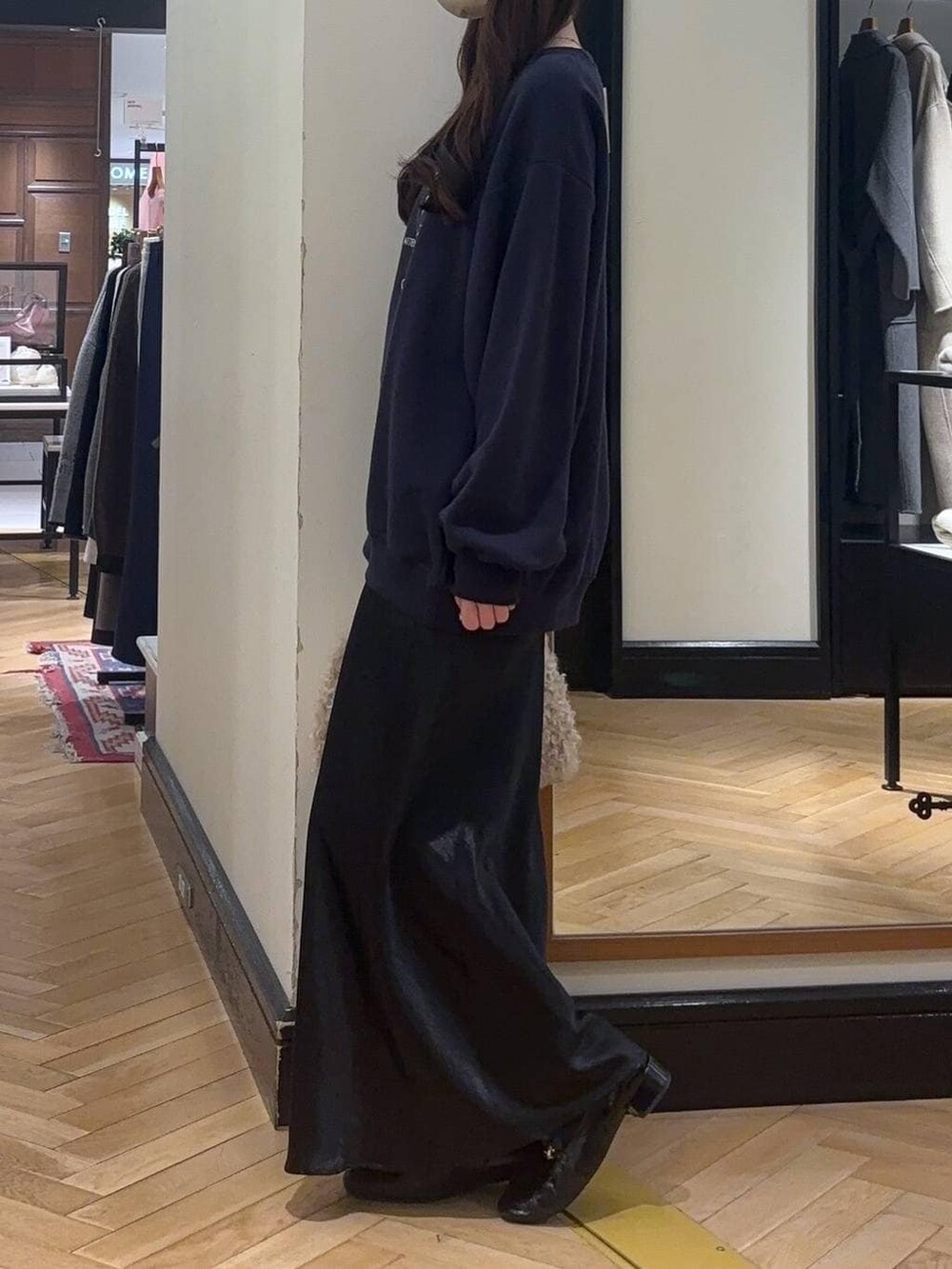 ブラック系のローファー、ブルー系のスカート、ベージュ系のハンドバッグを着用したレディースの秋コーディネートの3枚目の写真