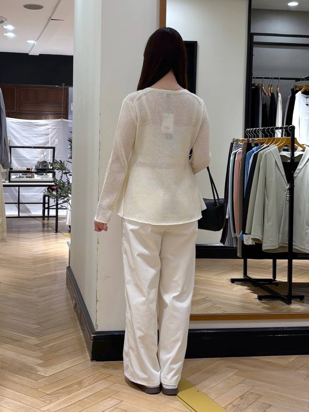 ホワイト系のスラックス、ブラック系のショルダーバッグ、ホワイト系のカーディガン/ボレロを着用したレディースの春コーディネートの4枚目の写真