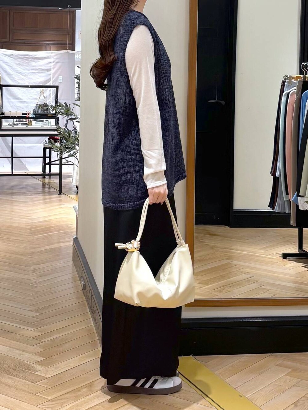 ブラック系のスカート、ブルー系のニット/セーター、ベージュ系のショルダーバッグを着用したレディースの春コーディネートの2枚目の写真