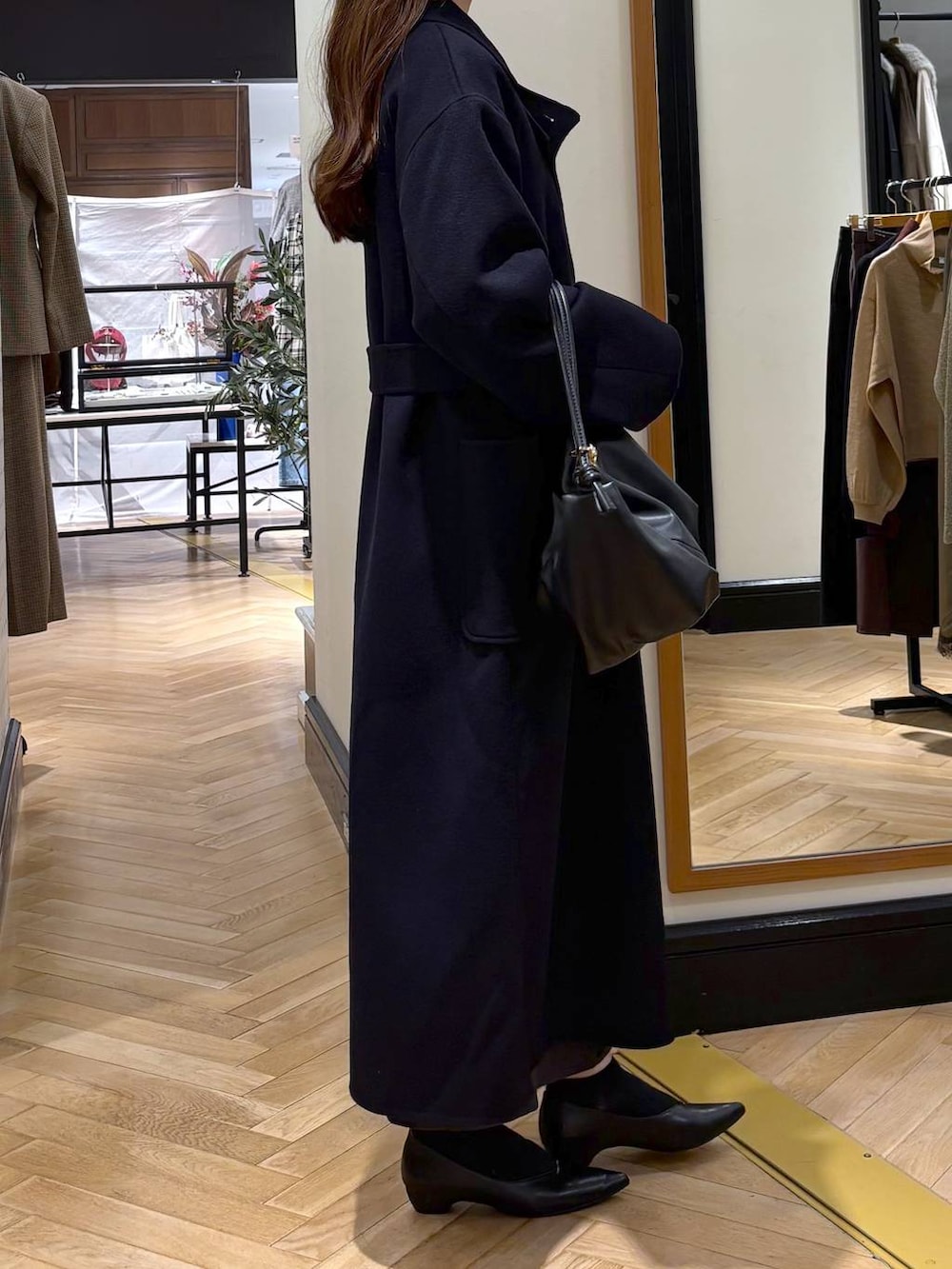 ブラック系のパンプス、ブルー系のステンカラーコート、ブラック系のショルダーバッグを着用したレディースの秋コーディネートの3枚目の写真