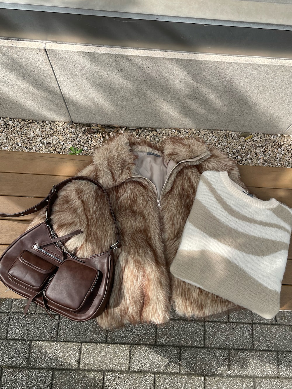 グレー系のブルゾン、ホワイト系のニット/セーター、ブラウン系のショルダーバッグを着用したレディースの秋コーディネートの3枚目の写真