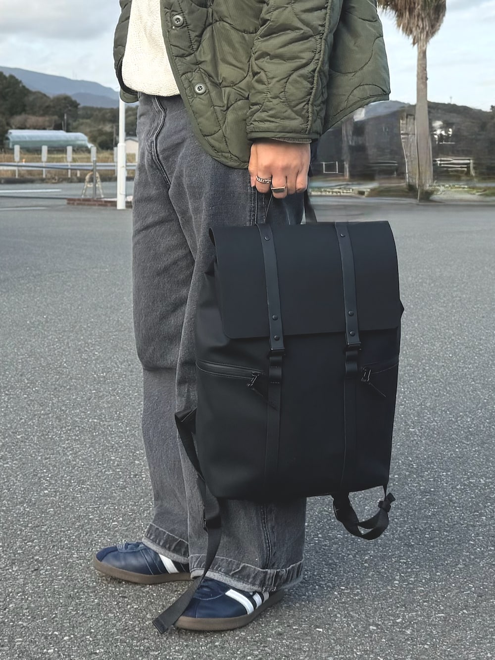 グリーン系のミリタリージャケット、ブラック系のバックパック/リュック、グレー系のデニムパンツを着用したメンズの春コーディネートの3枚目の写真