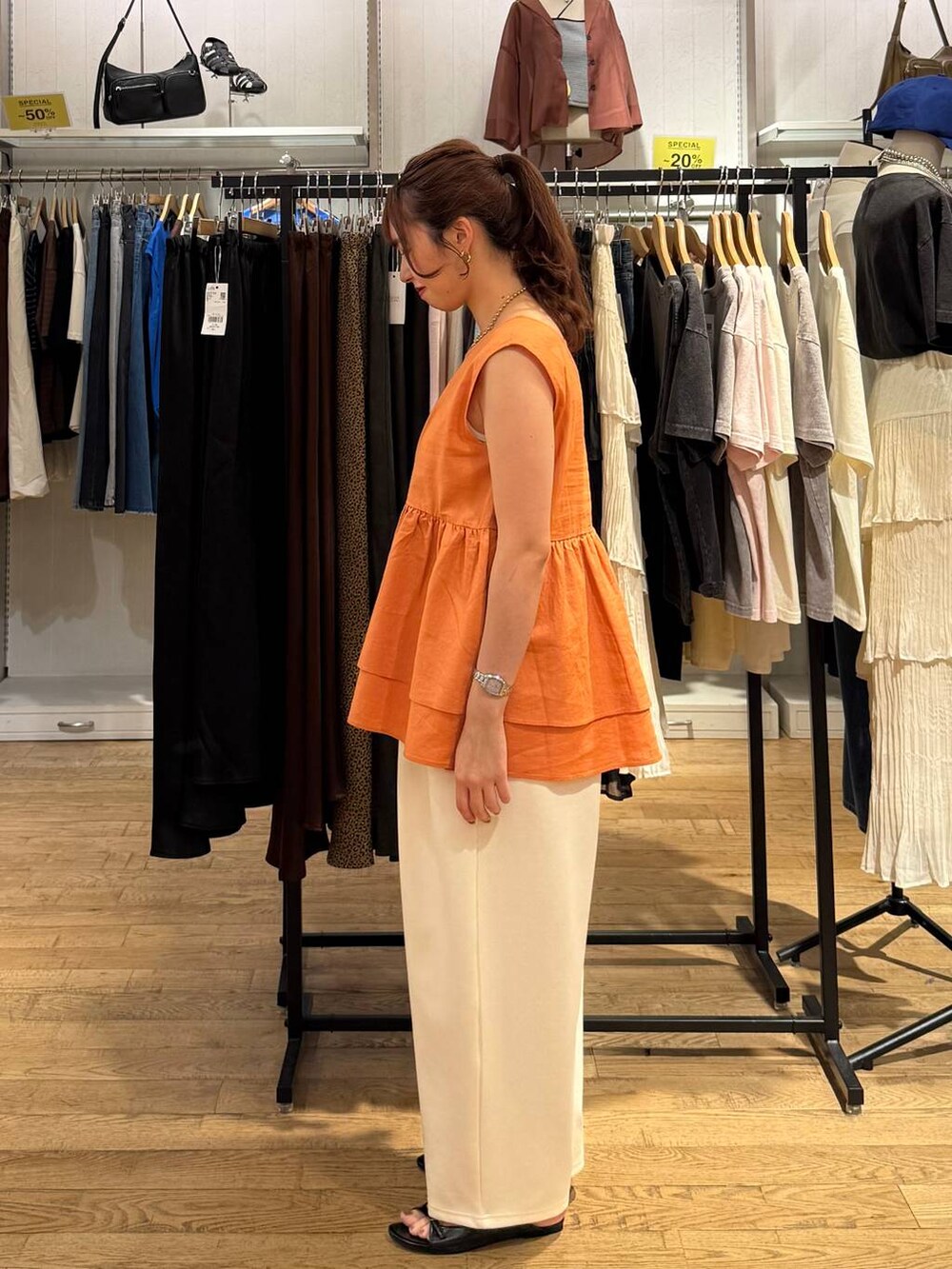 ベージュ系のデニムパンツ、ブラック系のサンダル、オレンジ系のTシャツ/カットソーを着用したレディースの夏コーディネートの2枚目の写真