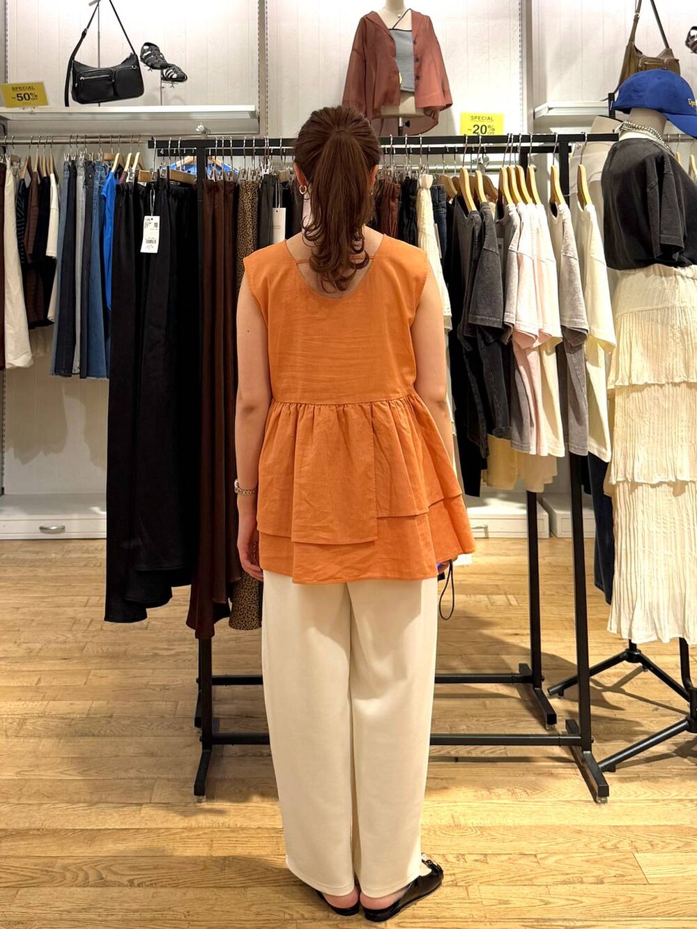 ベージュ系のデニムパンツ、ブラック系のサンダル、オレンジ系のTシャツ/カットソーを着用したレディースの夏コーディネートの3枚目の写真