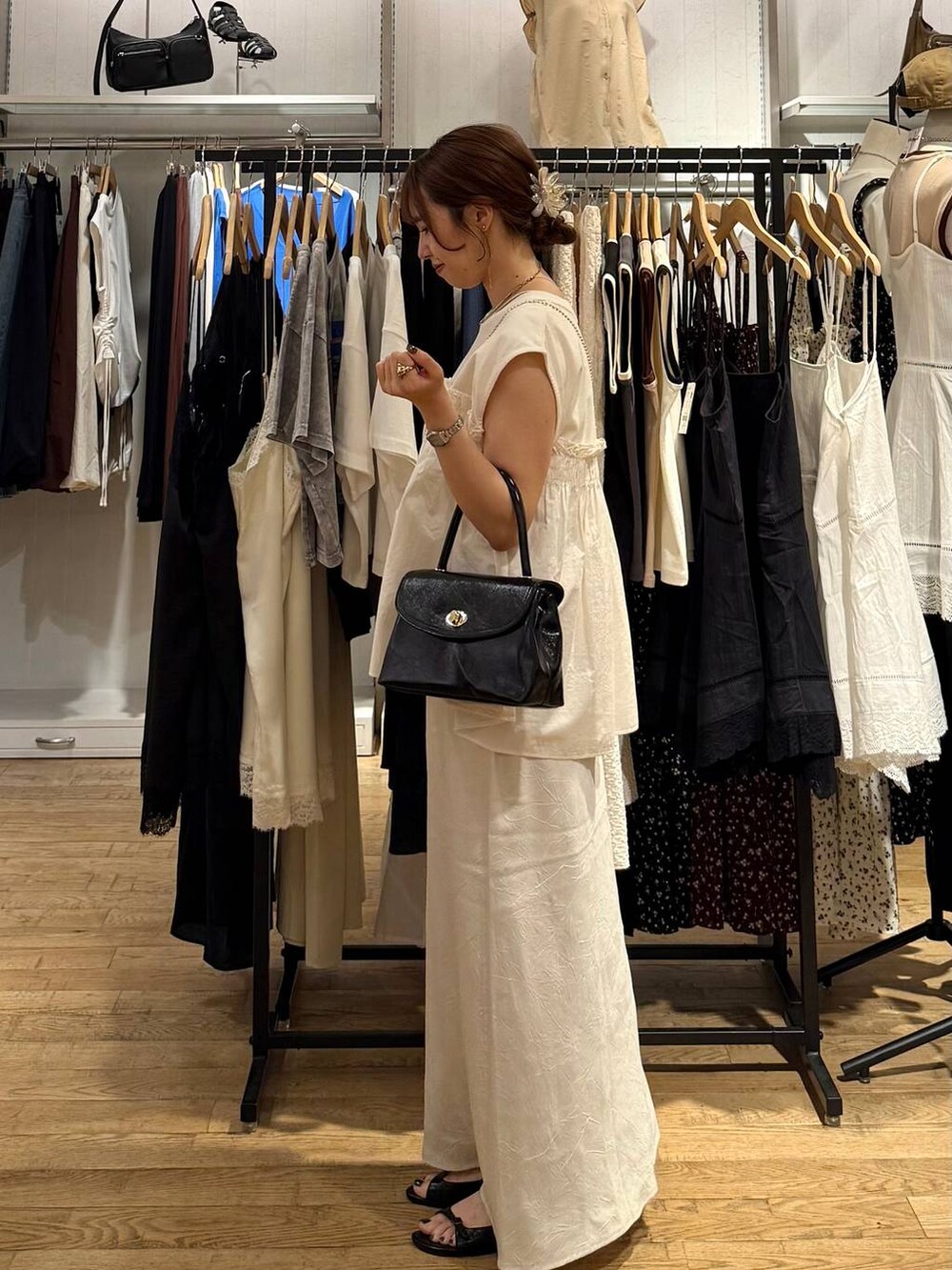 ホワイト系のスカート、ホワイト系のTシャツ/カットソー、ブラック系のサンダルを着用したレディースの夏コーディネートの2枚目の写真