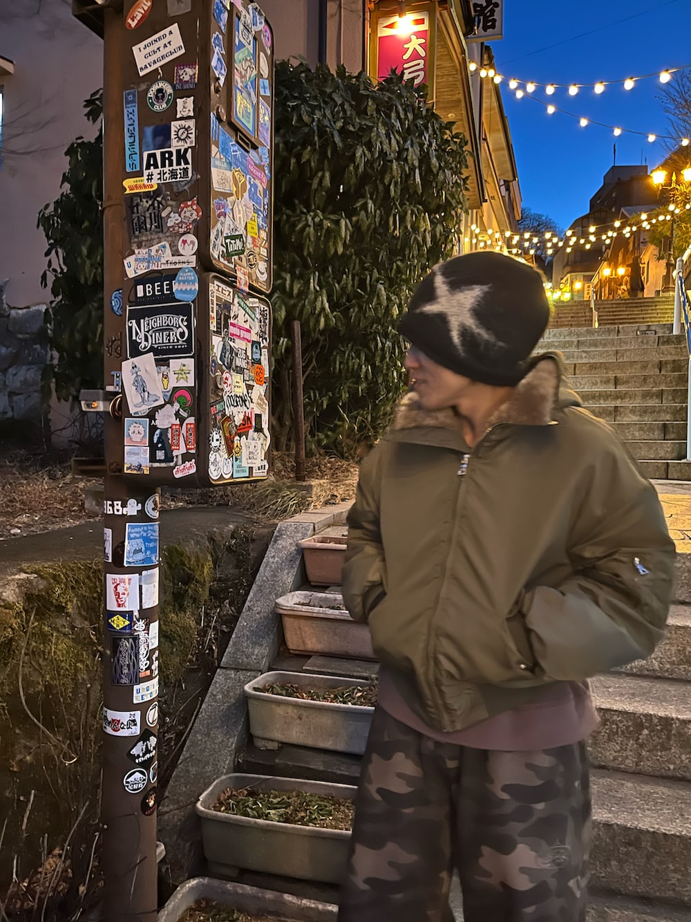 ブラウン系のTシャツ/カットソー、グレー系のスニーカー、グリーン系のジャケット/アウターを着用したメンズの冬コーディネートの2枚目の写真