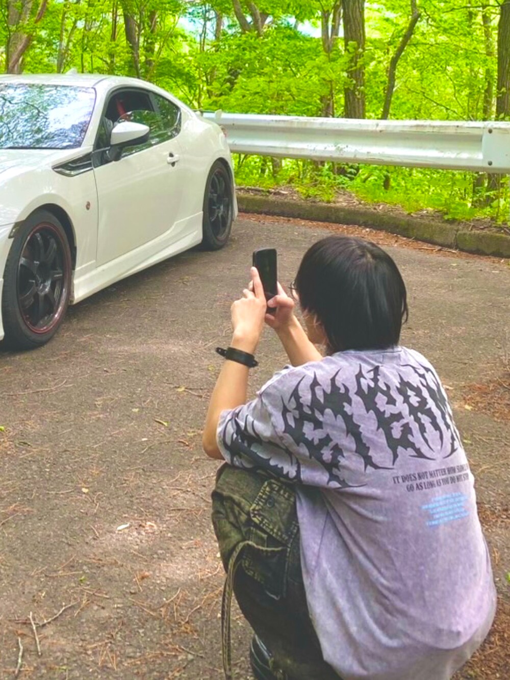 ブラック系のデニムパンツ、パープル系のTシャツ/カットソー、ブラック系のスニーカーを着用したメンズの春コーディネートの2枚目の写真