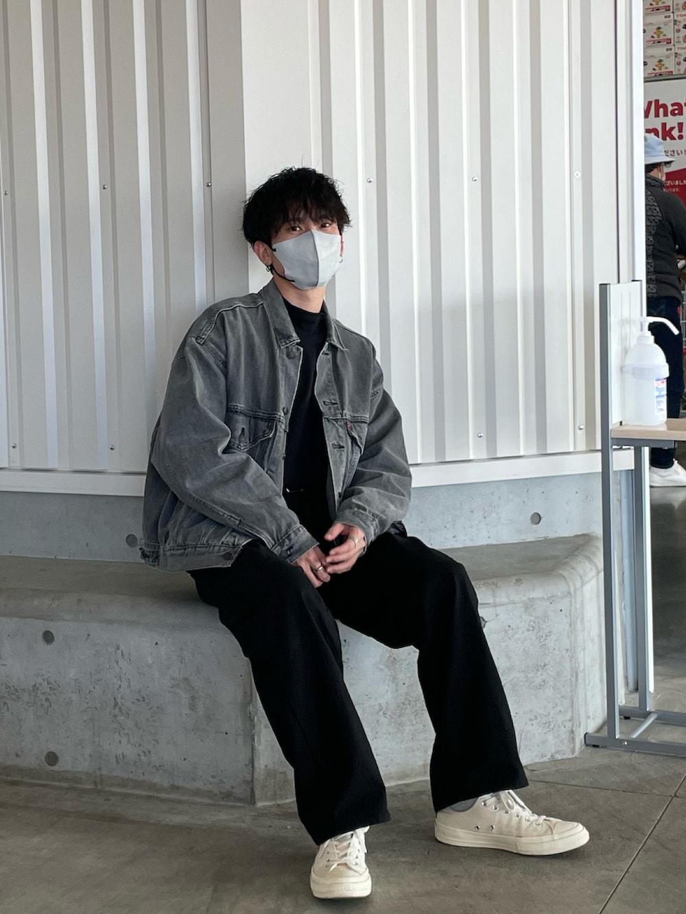 グレー系のデニムジャケット、ブラック系のパンツ、ホワイト系のスニーカーを着用したメンズの秋コーディネートの2枚目の写真