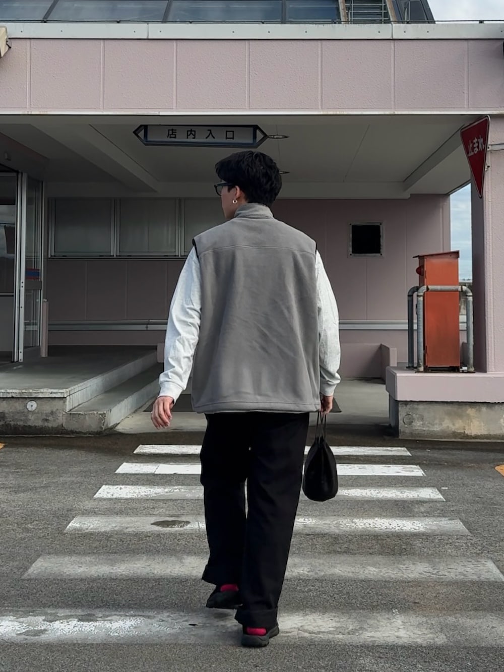 グレー系のベスト、ホワイト系のTシャツ/カットソー、ブラック系のデニムパンツを着用したメンズの秋コーディネートの2枚目の写真