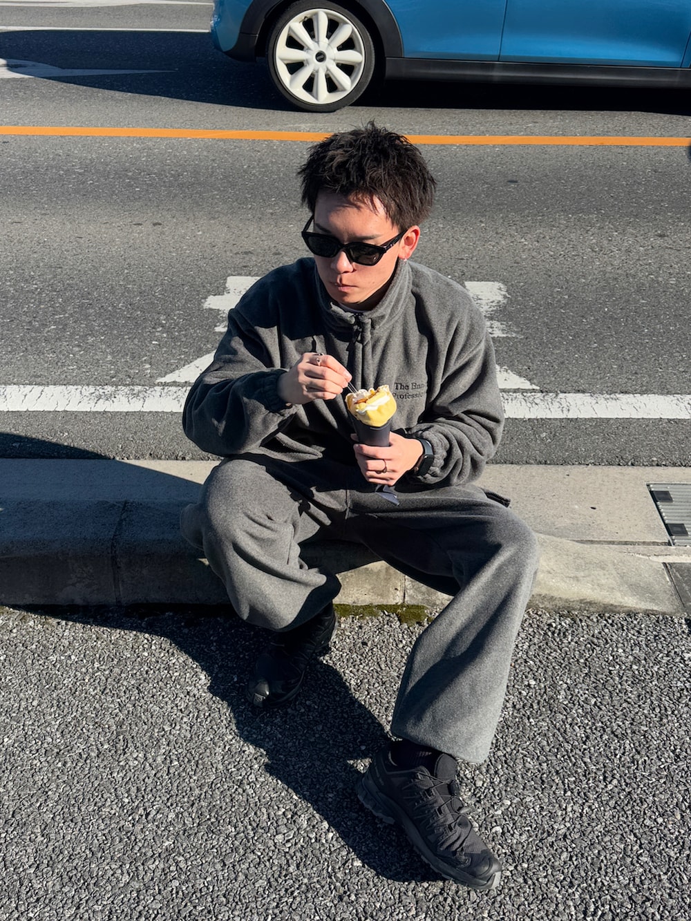 グレー系のその他アウター、ブラック系のスニーカー、ブラック系のサングラスを着用したメンズの冬コーディネートの2枚目の写真