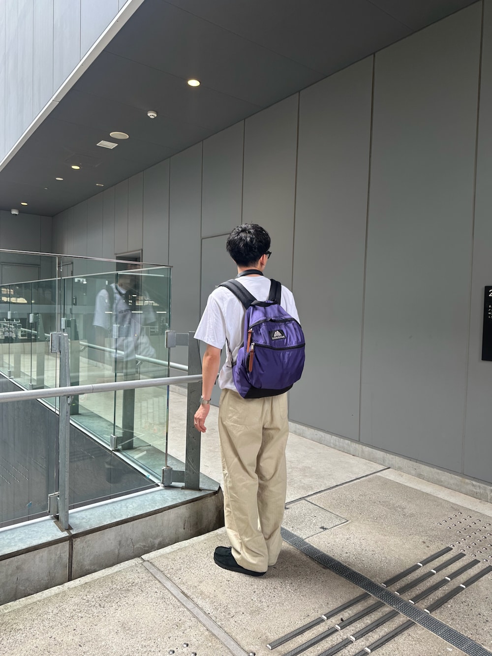 ホワイト系のTシャツ/カットソー、パープル系のバックパック/リュック、ベージュ系のチノパンツを着用したメンズの秋コーディネートの2枚目の写真