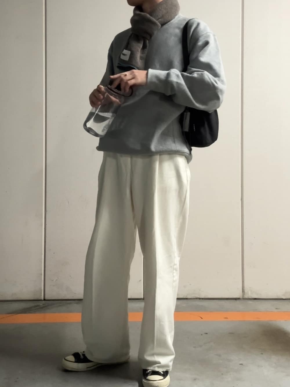 ホワイト系のデニムパンツ、グレー系のスウェット、ブラック系のハンドバッグを着用したメンズの秋コーディネートの2枚目の写真