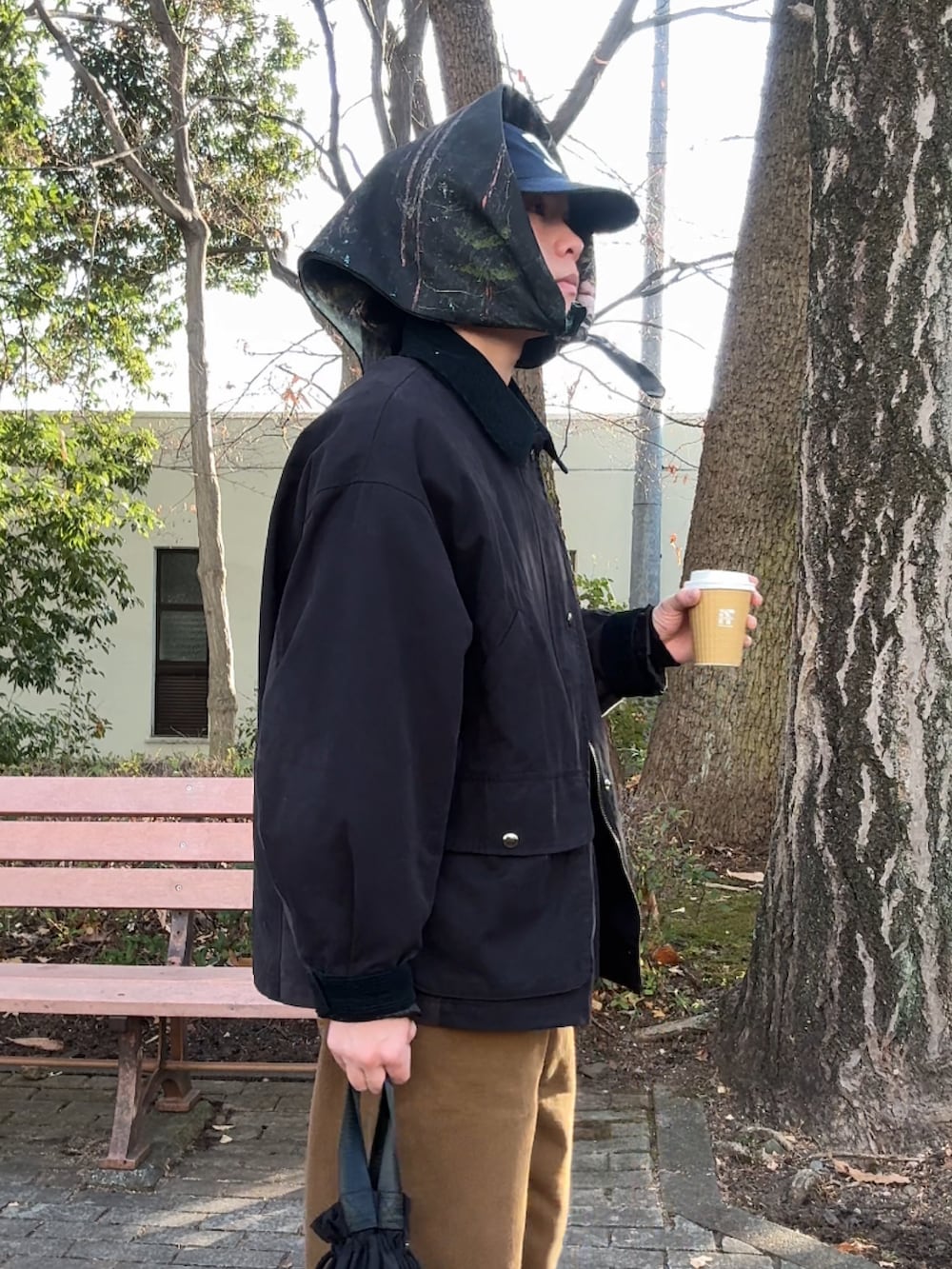 ブラック系のブルゾン、ブラウン系のチノパンツ、ブラック系のハンドバッグを着用したメンズの冬コーディネートの2枚目の写真