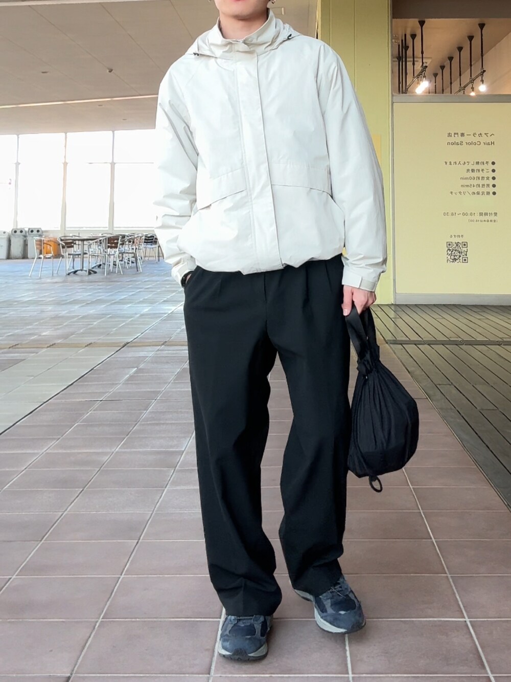 ホワイト系のブルゾン、ブラック系のスラックス、ブルー系のスニーカーを着用したメンズの冬コーディネートの2枚目の写真