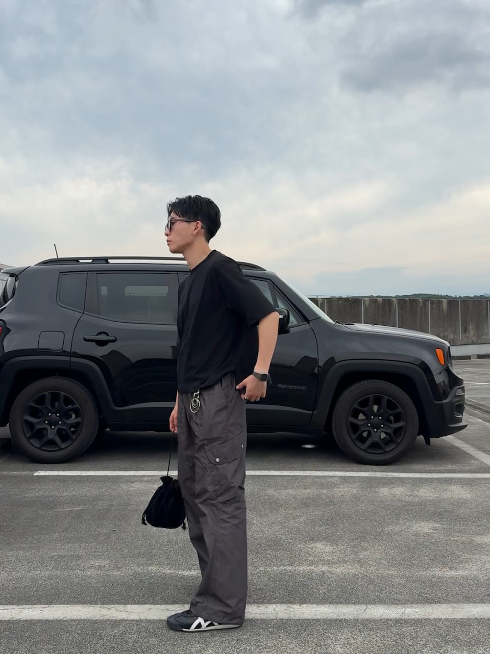 ブラック系のTシャツ/カットソー、ブラック系のハンドバッグ、グレー系のカーゴパンツを着用したメンズの夏コーディネートの2枚目の写真