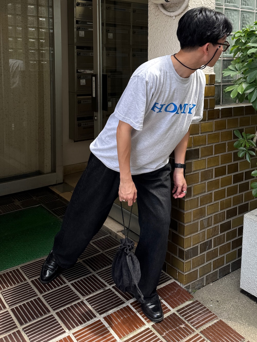 ブラック系のデニムパンツ、ブラック系のローファー、グレー系のTシャツ/カットソーを着用したメンズの夏コーディネートの2枚目の写真