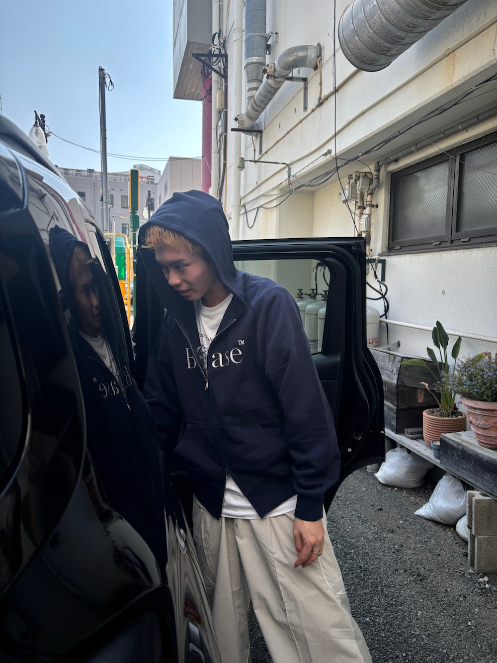 ブルー系のパーカー、ブラック系のモカシン/デッキシューズ、ホワイト系のパンツを着用したメンズの秋コーディネートの2枚目の写真