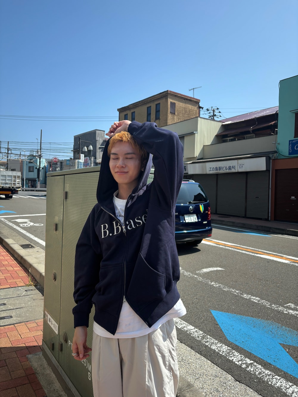 ブルー系のパーカー、ブラック系のモカシン/デッキシューズ、ホワイト系のパンツを着用したメンズの秋コーディネートの3枚目の写真