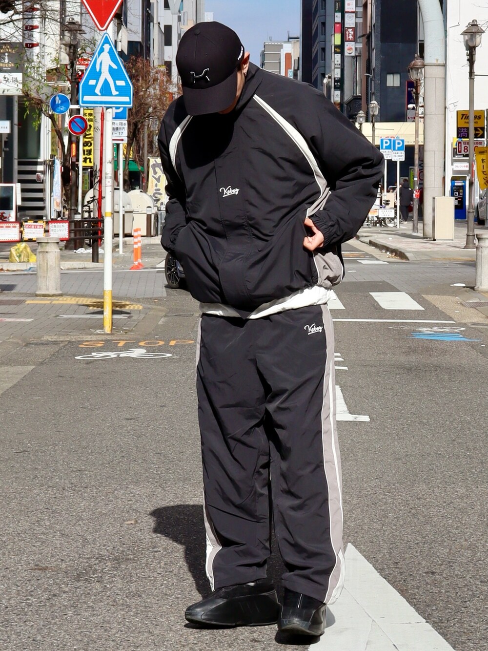 ブラック系のナイロンジャケット、ブラック系のその他パンツ、ブラック系のキャップを着用したメンズの冬コーディネートの3枚目の写真