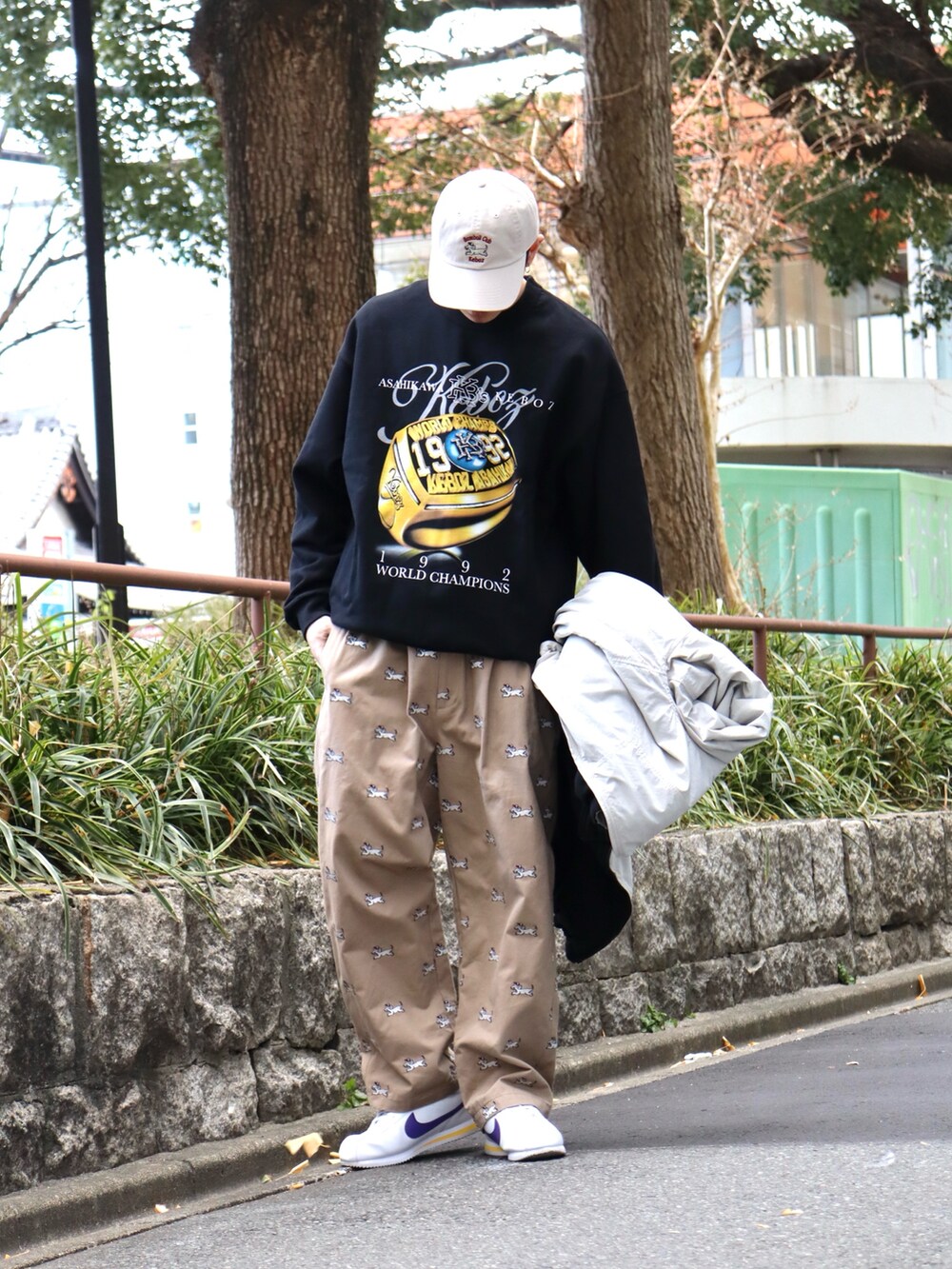 ブラック系のナイロンジャケット、ブラック系のスウェット、ベージュ系のチノパンツを着用したメンズの冬コーディネートの3枚目の写真