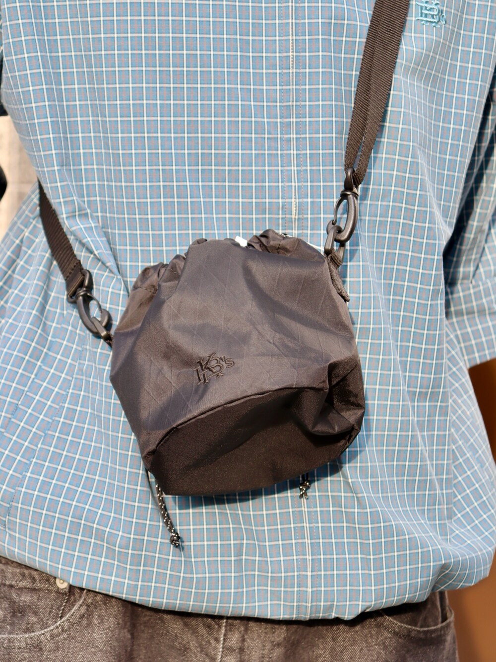 ブルー系のブルゾン、ブラック系のショルダーバッグ、ブラック系のデニムパンツを着用したメンズの春コーディネートの4枚目の写真