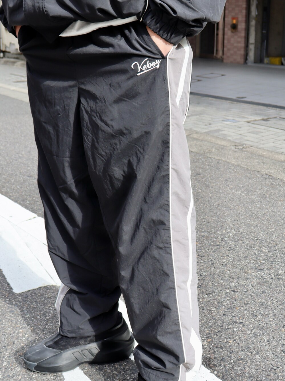 ブラック系のナイロンジャケット、ブラック系のその他パンツ、ブラック系のキャップを着用したメンズの冬コーディネートの7枚目の写真