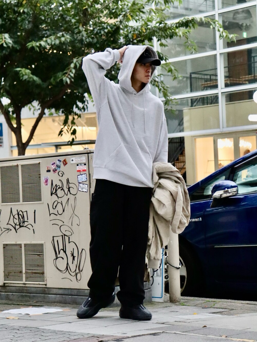 ベージュ系のブルゾン、グレー系のパーカー、ブラック系のカーゴパンツを着用したメンズの秋コーディネートの3枚目の写真