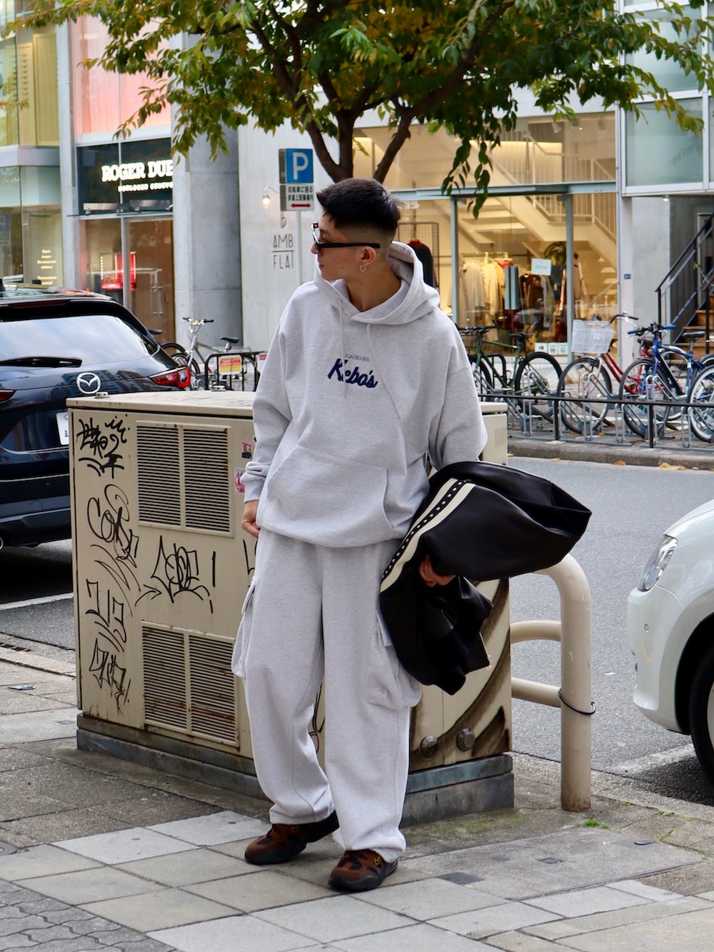 グレー系のパーカー、グレー系のスウェットパンツ、ブラック系のスタジャンを着用したメンズの冬コーディネートの3枚目の写真