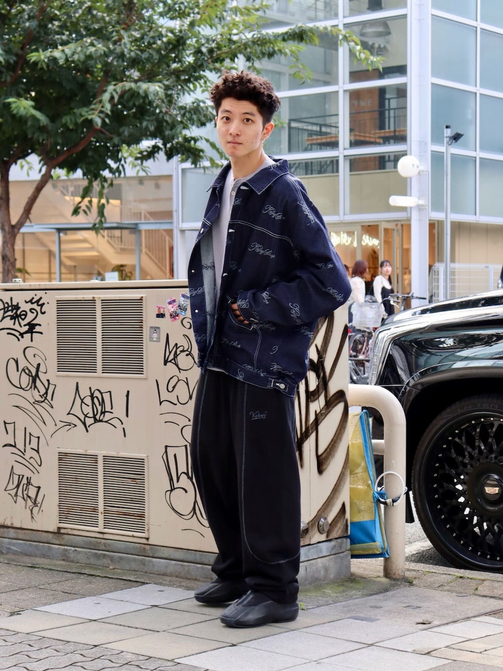 グレー系のTシャツ/カットソー、ブルー系のデニムジャケット、ブラック系のスウェットパンツを着用したメンズの秋コーディネートの2枚目の写真